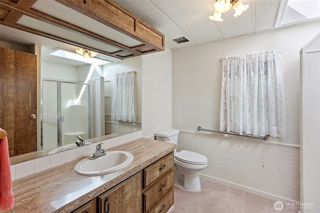 bathroom featuring vanity, visible vents, toilet, and a shower stall