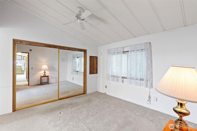 unfurnished bedroom with multiple windows, carpet, vaulted ceiling, and ceiling fan