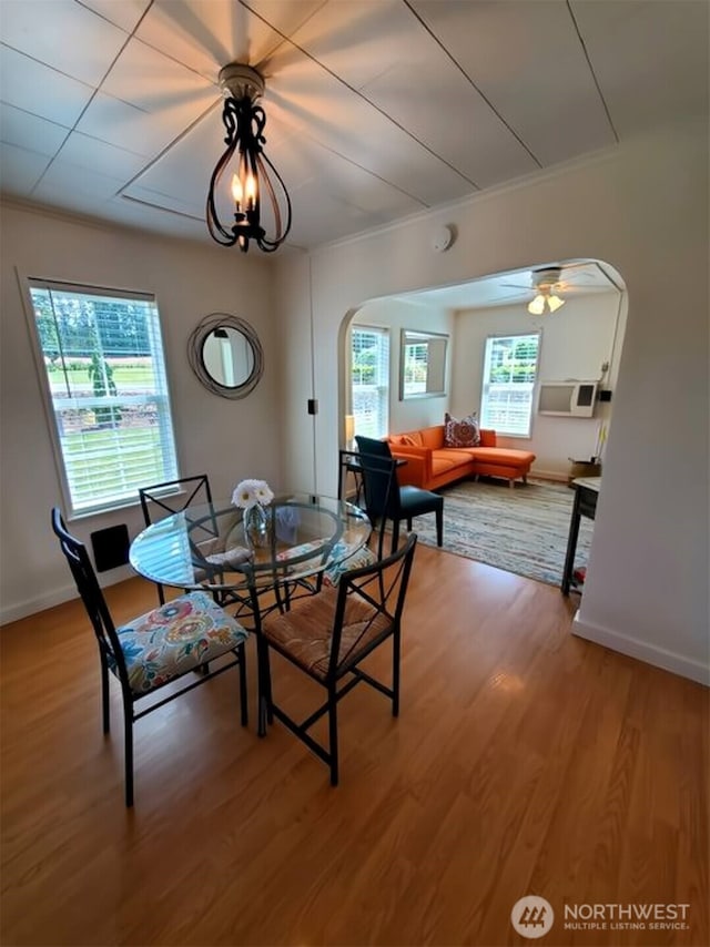 dining room with a ceiling fan, ornamental molding, wood finished floors, baseboards, and arched walkways