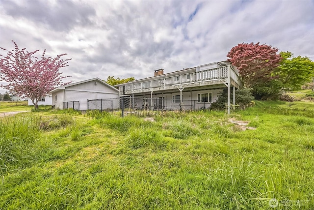 rear view of property with a chimney, fence, and a wooden deck