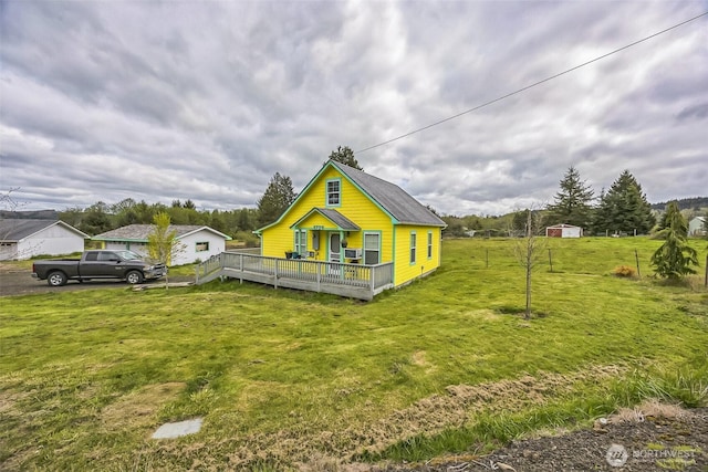 exterior space with a lawn, a wooden deck, and an outbuilding