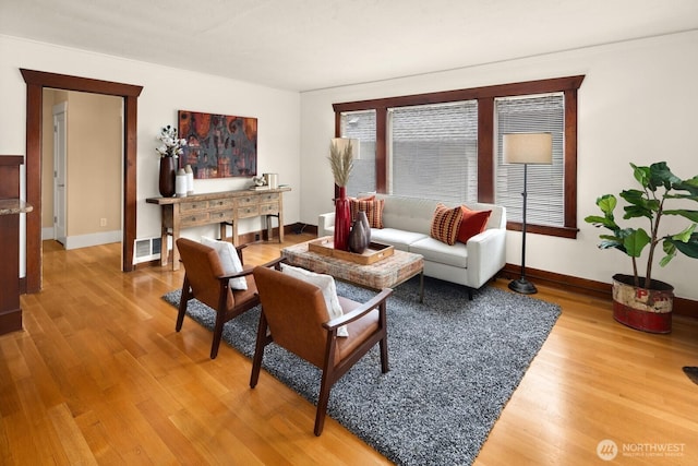 living area with baseboards, light wood finished floors, and visible vents