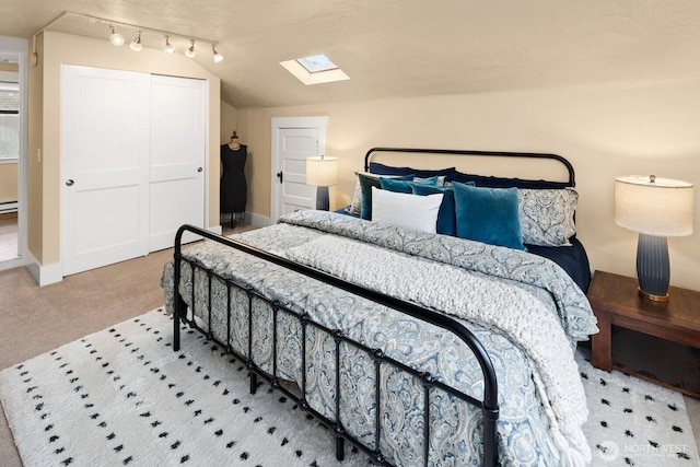 bedroom featuring vaulted ceiling with skylight, carpet floors, baseboards, and a closet