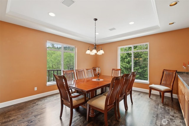 dining area featuring plenty of natural light, a raised ceiling, dark wood-style flooring, and a chandelier