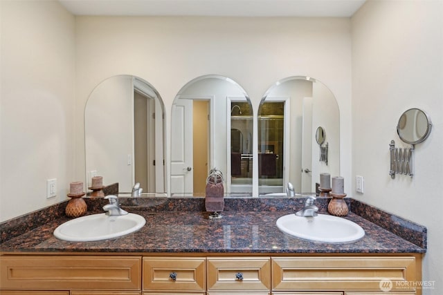bathroom with double vanity, a sink, and a stall shower