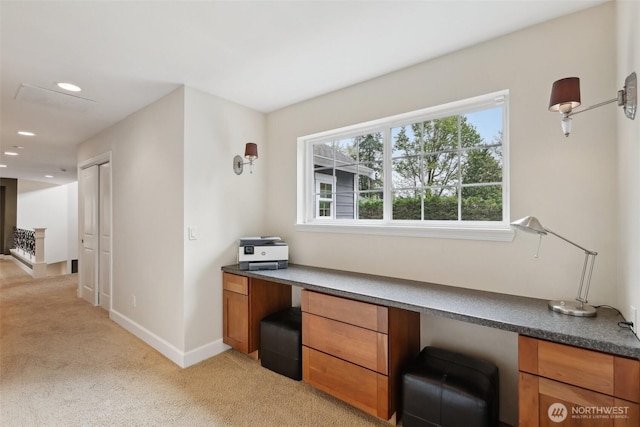 office space featuring baseboards, recessed lighting, built in desk, and light colored carpet