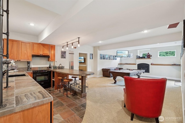 kitchen featuring black electric range oven, pool table, baseboards, open floor plan, and under cabinet range hood