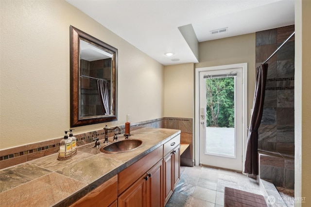 full bathroom with a shower with curtain, visible vents, wainscoting, and vanity