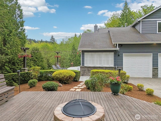 deck featuring an attached garage and an outdoor fire pit