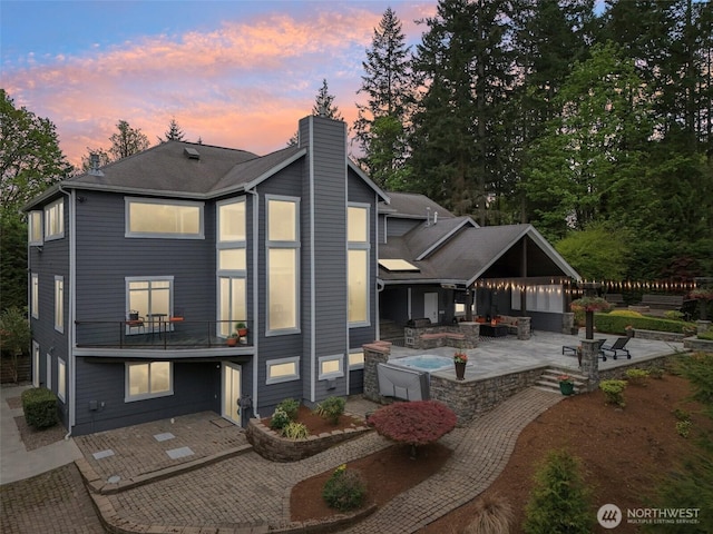 back of property with an outdoor living space, a patio area, and a chimney