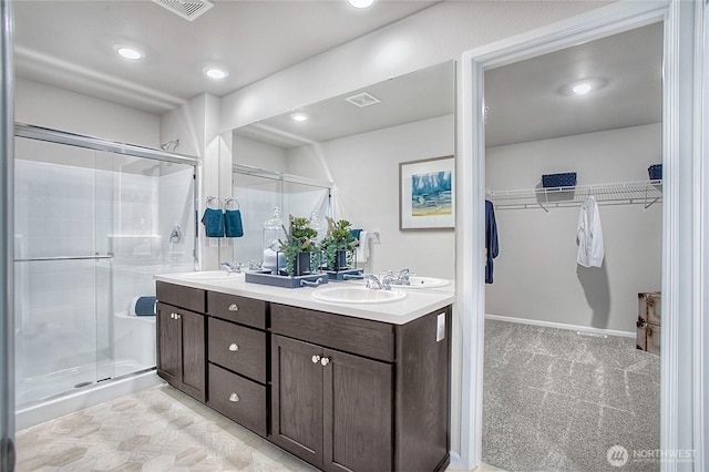 bathroom with double vanity, a sink, a spacious closet, and a shower stall