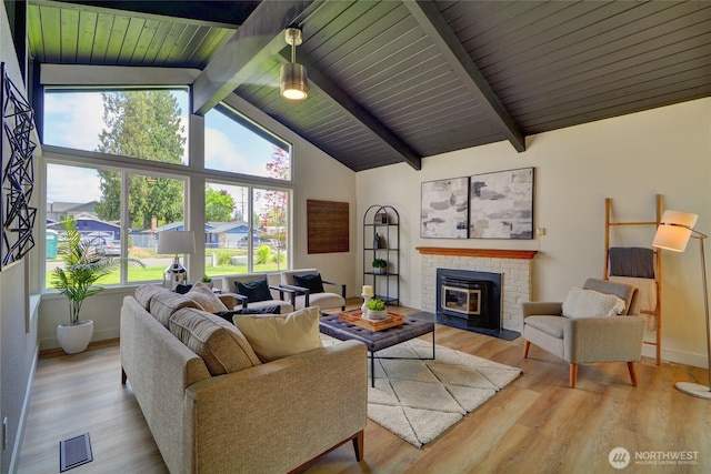 living area featuring visible vents, a brick fireplace, wood finished floors, beam ceiling, and baseboards