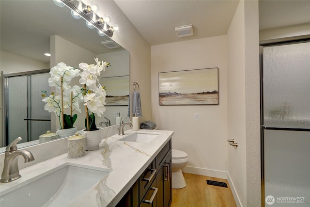 bathroom featuring toilet, visible vents, a sink, and wood finished floors