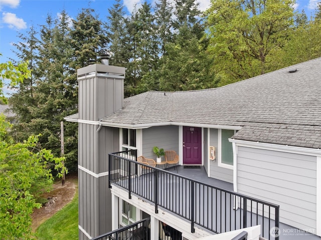 exterior space with roof with shingles and a chimney