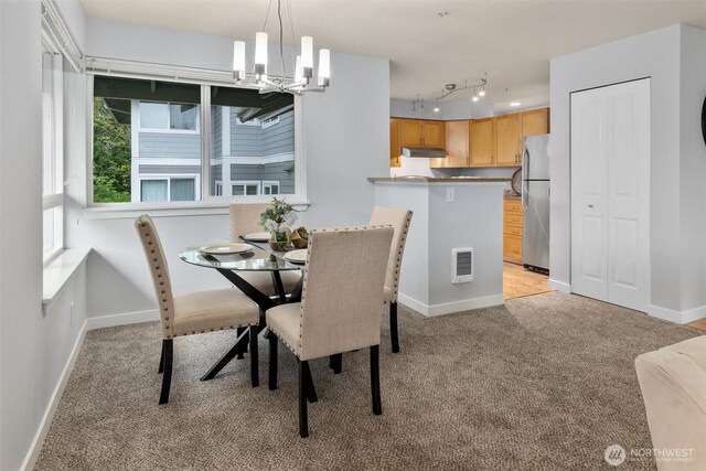dining area featuring light colored carpet, baseboards, and an inviting chandelier