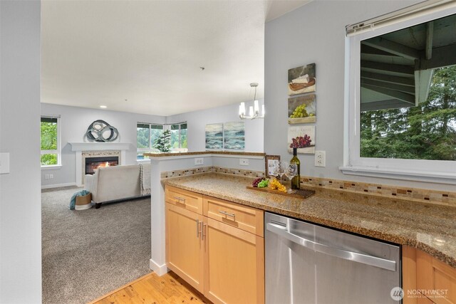 kitchen with a notable chandelier, light wood-style floors, dishwasher, a glass covered fireplace, and open floor plan