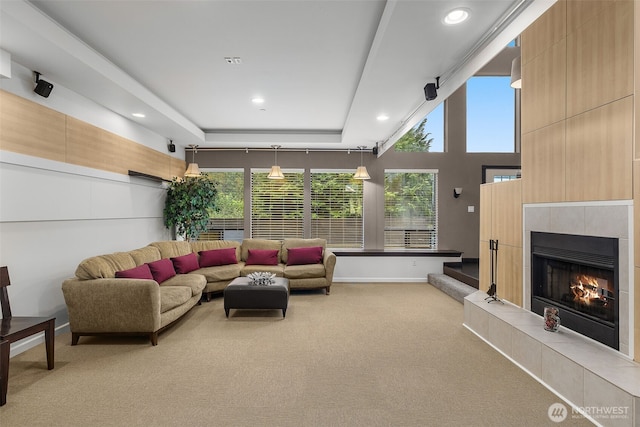 living area with light colored carpet, recessed lighting, a tray ceiling, and a tile fireplace
