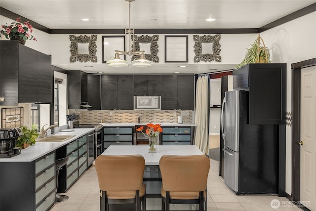 kitchen featuring decorative backsplash, white microwave, light countertops, range with two ovens, and a sink