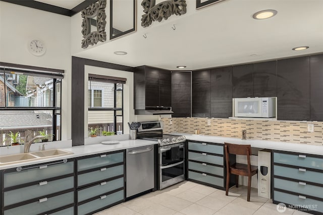 kitchen with decorative backsplash, appliances with stainless steel finishes, a sink, light tile patterned floors, and light countertops
