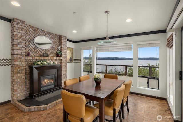 dining room featuring baseboards, recessed lighting, a water view, and a fireplace