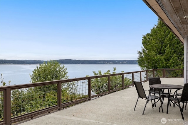 balcony with a water view and outdoor dining space