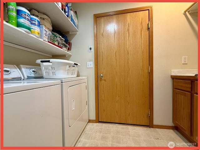 washroom featuring washing machine and clothes dryer, cabinet space, and baseboards