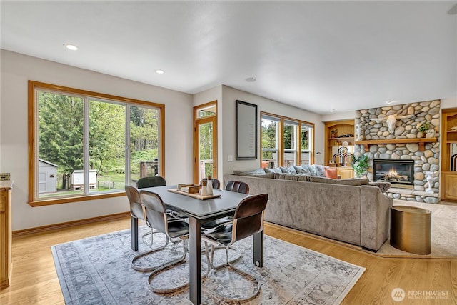 dining area with light wood-style floors, plenty of natural light, and a fireplace