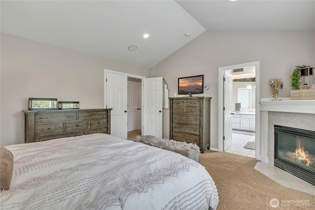 carpeted bedroom featuring tile patterned flooring, recessed lighting, connected bathroom, a tiled fireplace, and vaulted ceiling