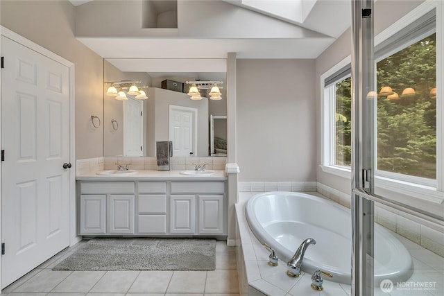 bathroom featuring a sink, an inviting chandelier, a garden tub, and double vanity