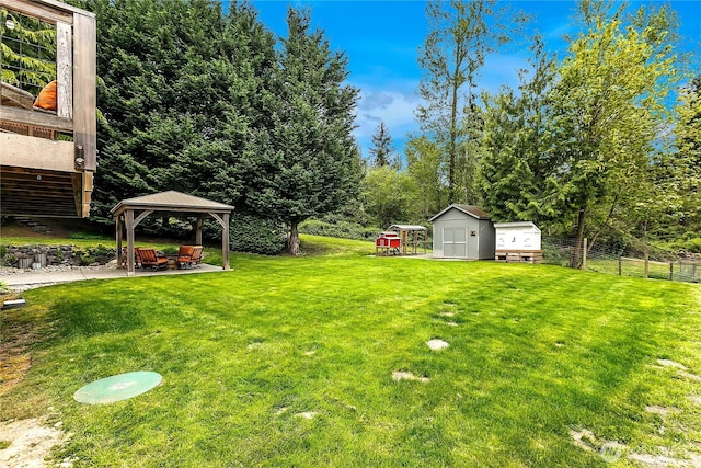 view of yard featuring fence, a patio area, a gazebo, a storage shed, and an outbuilding