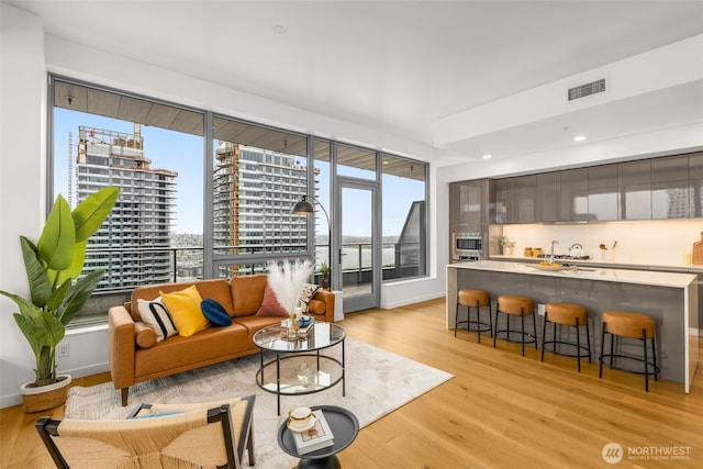 living area featuring visible vents, recessed lighting, light wood-style floors, and plenty of natural light