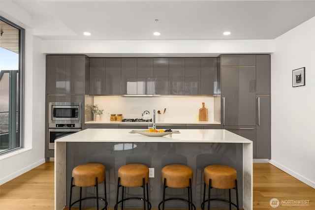 kitchen featuring built in appliances, modern cabinets, gray cabinetry, and a kitchen breakfast bar