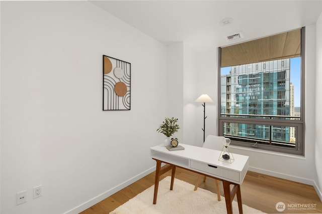 office space featuring baseboards, visible vents, and wood finished floors