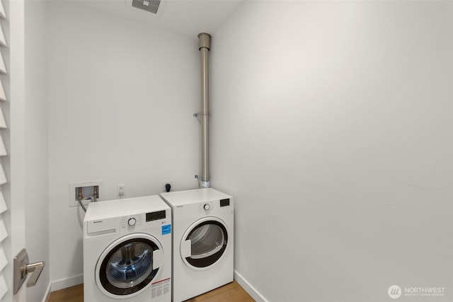 clothes washing area with laundry area, light wood-style flooring, baseboards, visible vents, and washing machine and dryer