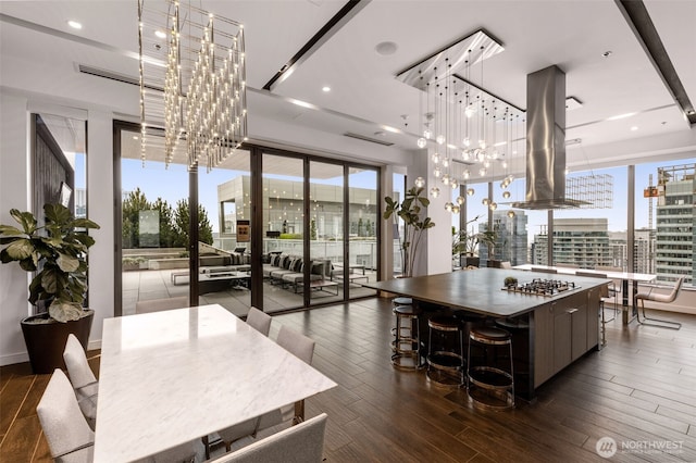 kitchen with stainless steel gas cooktop, dark wood-style flooring, a large island, and a notable chandelier