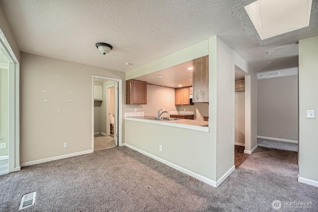 kitchen featuring light countertops, visible vents, a sink, and carpet