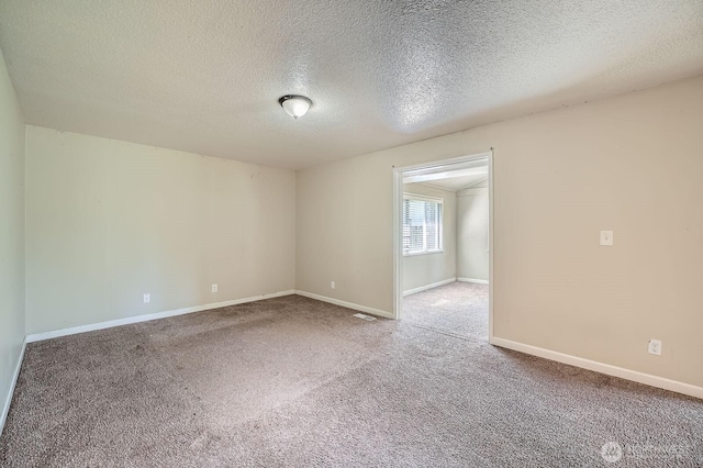 spare room featuring carpet floors, a textured ceiling, baseboards, and visible vents