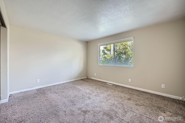 spare room featuring carpet floors, baseboards, and a textured ceiling
