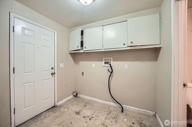 washroom with baseboards, washer hookup, and cabinet space