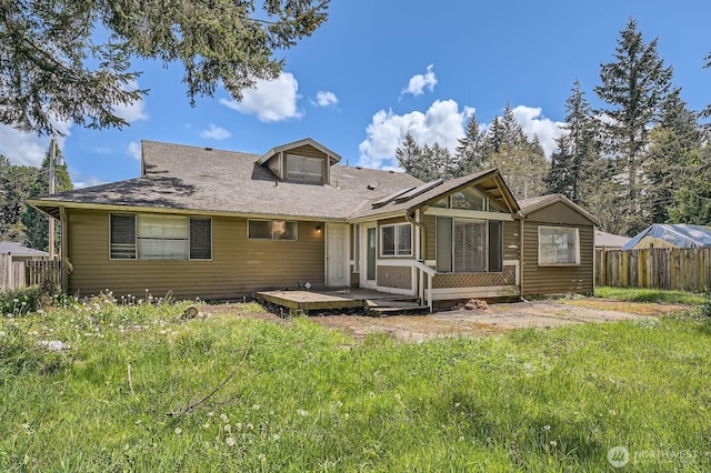 rear view of house featuring fence, a yard, and a deck