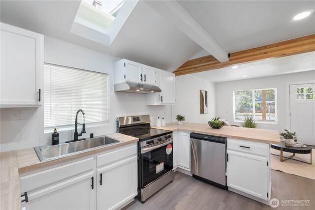 916 S Sheridan Ave, Tacoma, WA 98405 - kitchen featuring stainless steel appliances, a peninsula, under cabinet range hood, recessed lighting, and a skylight