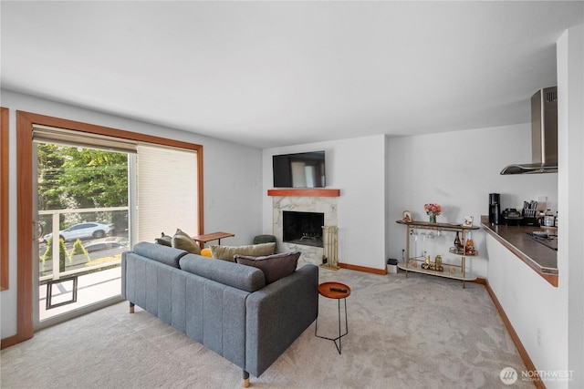living room featuring a premium fireplace, baseboards, and light colored carpet