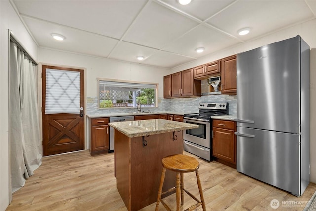 19003 129th Ave NE, Bothell, WA 98011 - kitchen with appliances with stainless steel finishes, light wood finished floors, backsplash, a center island, and a sink