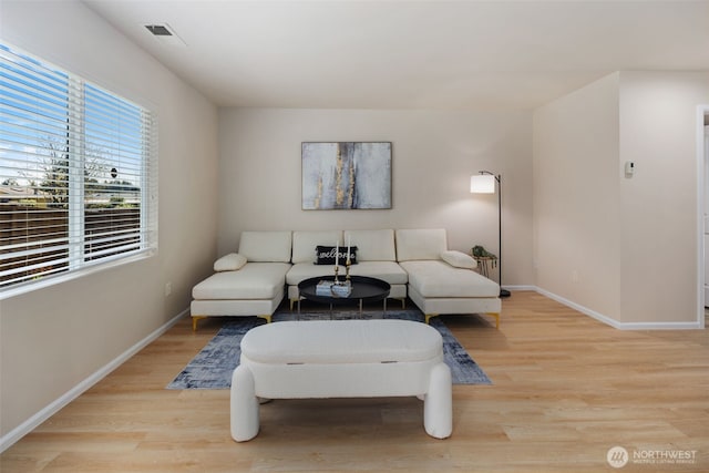 living area featuring baseboards, visible vents, and light wood finished floors