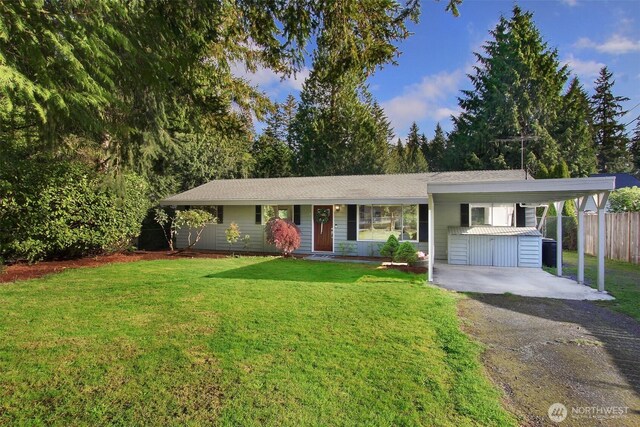 ranch-style home with an attached carport, aphalt driveway, fence, and a front yard