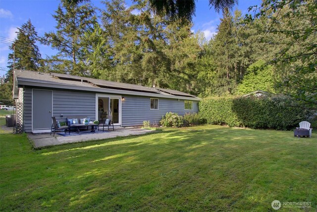 back of house with a yard, a patio, outdoor lounge area, and roof mounted solar panels