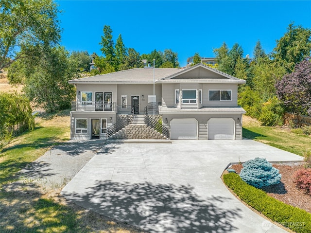 raised ranch featuring concrete driveway, stairs, and a garage