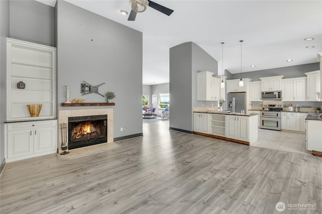 living room with a fireplace, high vaulted ceiling, recessed lighting, a ceiling fan, and light wood-style flooring