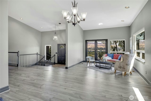 living room featuring baseboards, high vaulted ceiling, wood finished floors, and a chandelier
