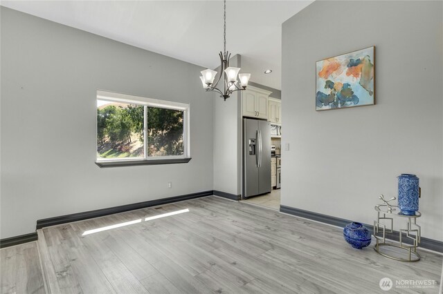 unfurnished dining area with baseboards, recessed lighting, light wood-style floors, and a notable chandelier